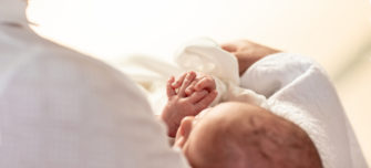 A baby in white held at a Baptism